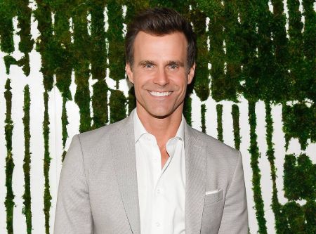 Cameron Mathison in a grey suit poses for a picture.